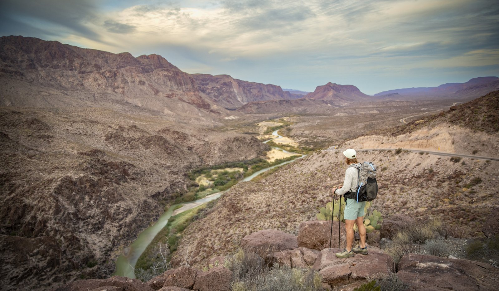 Man standing on a hill looking down at a river.