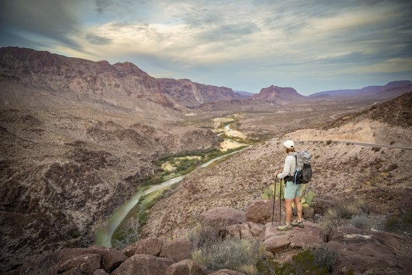 Man standing on a hill looking down at a river.