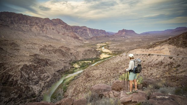 Man standing on a hill looking down at a river.