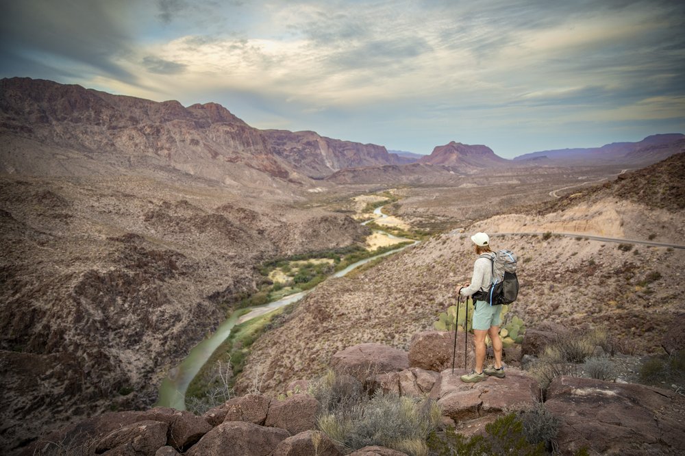 Man standing on a hill looking down at a river.