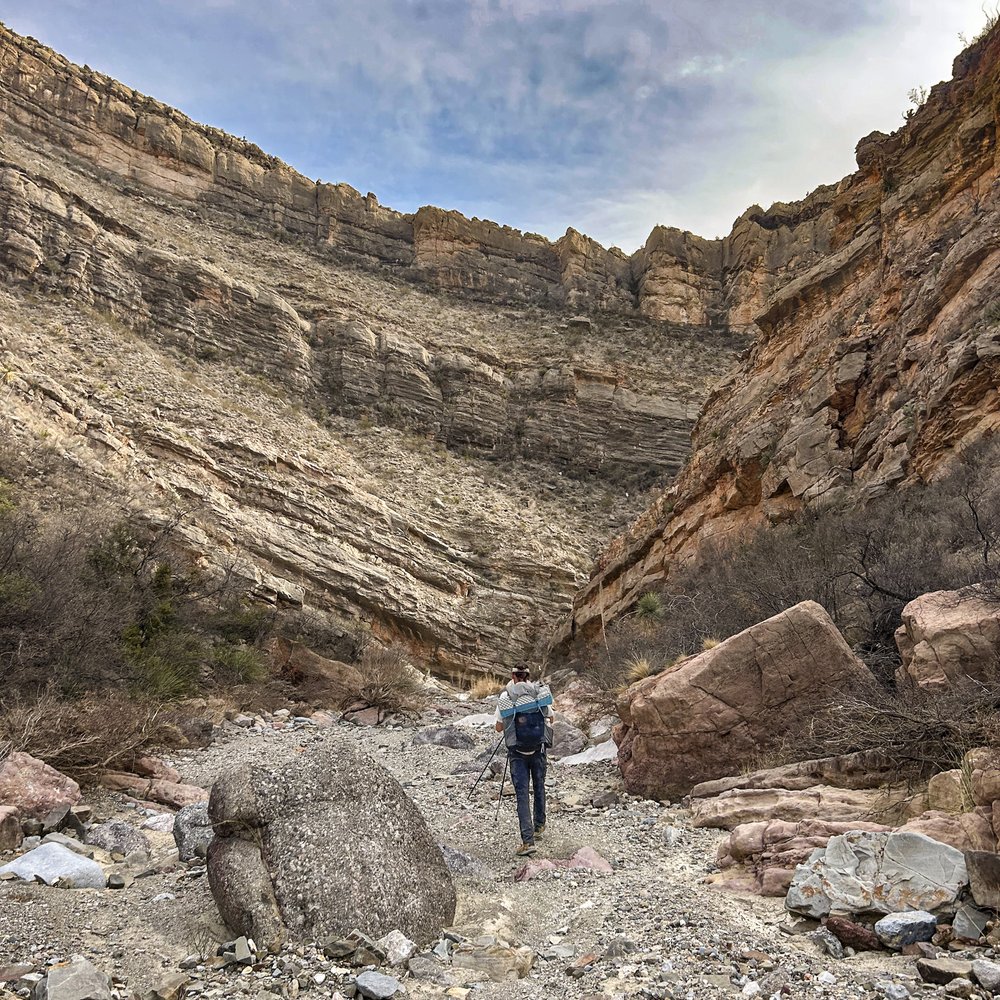A person with a back pack walking a trail in a canyon at Big Bend Ranch State Park.