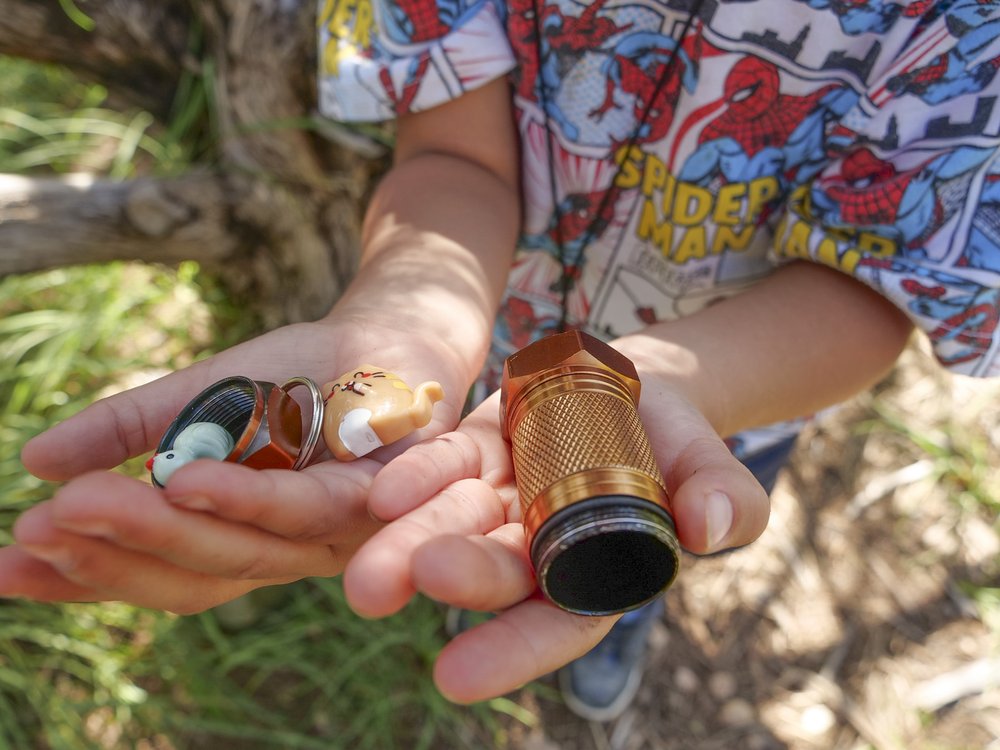 A child in a spiderman shirt holding a monocle and toys.