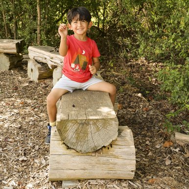 A boy straddling a bench in a state park.