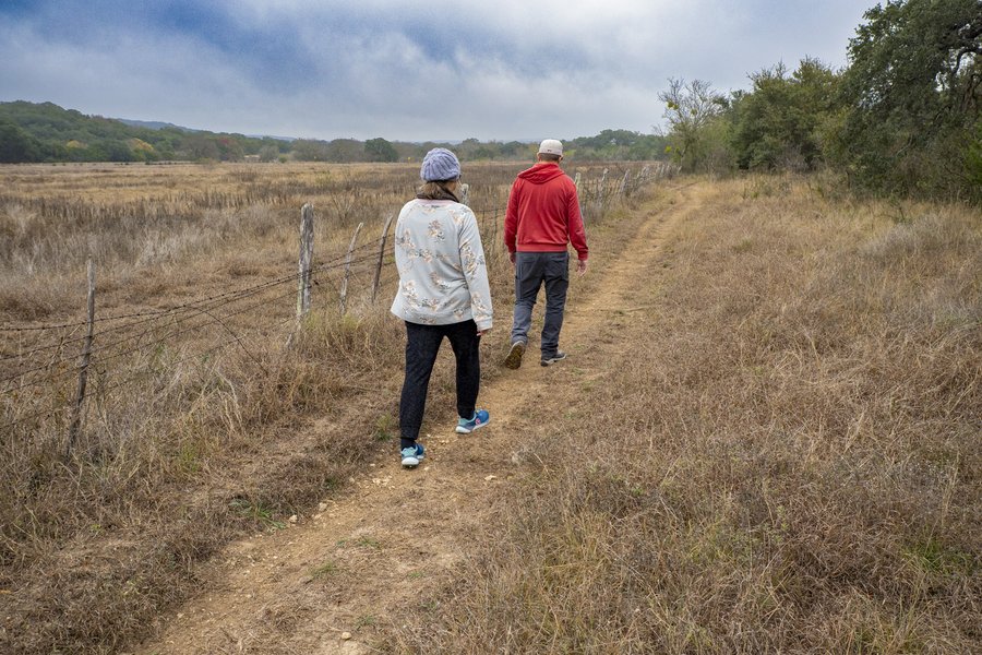 People walking a trail near a fence line.
