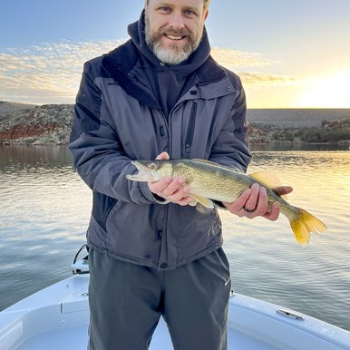 A man poses with a walleye fish on a boat on the lake