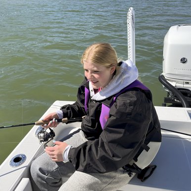 A young girl sitting on a boat fishing