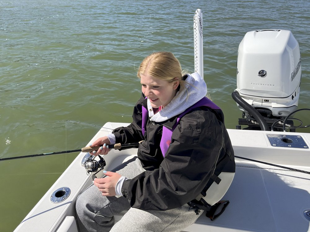 A young girl sitting on a boat fishing
