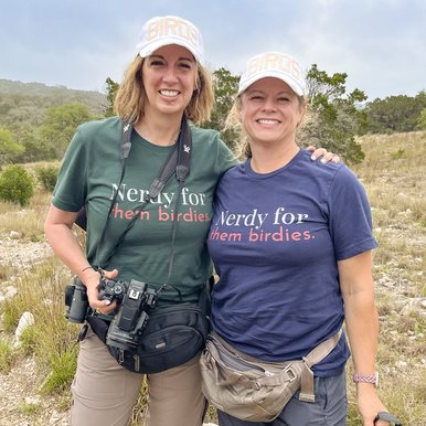 Two ladies pose for a photo wearing shirts that say "Nerdy for them birdies"