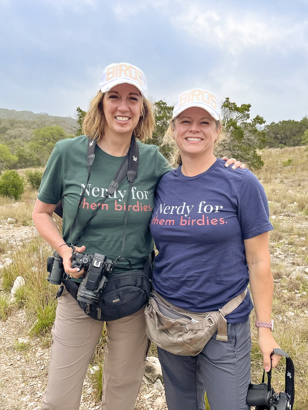Two ladies pose for a photo wearing shirts that say "Nerdy for them birdies"