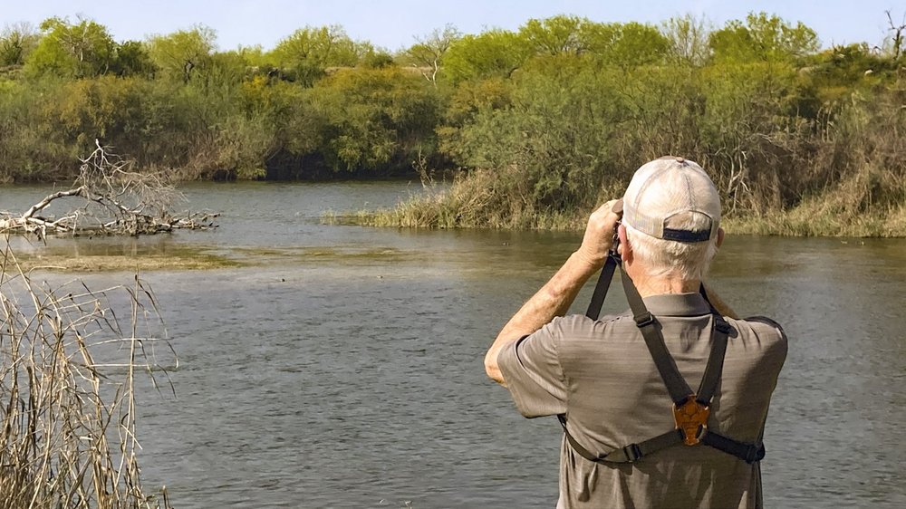 A man with binoculars looks out over the water