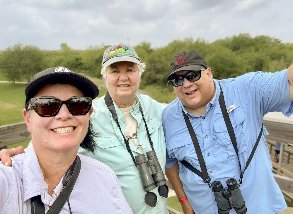 A family smiling and posing for the camera while wearing binoculars