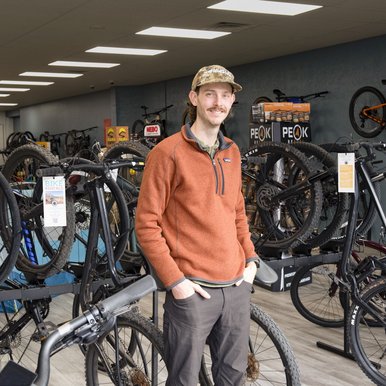 A man standing in front of bikes for sale.