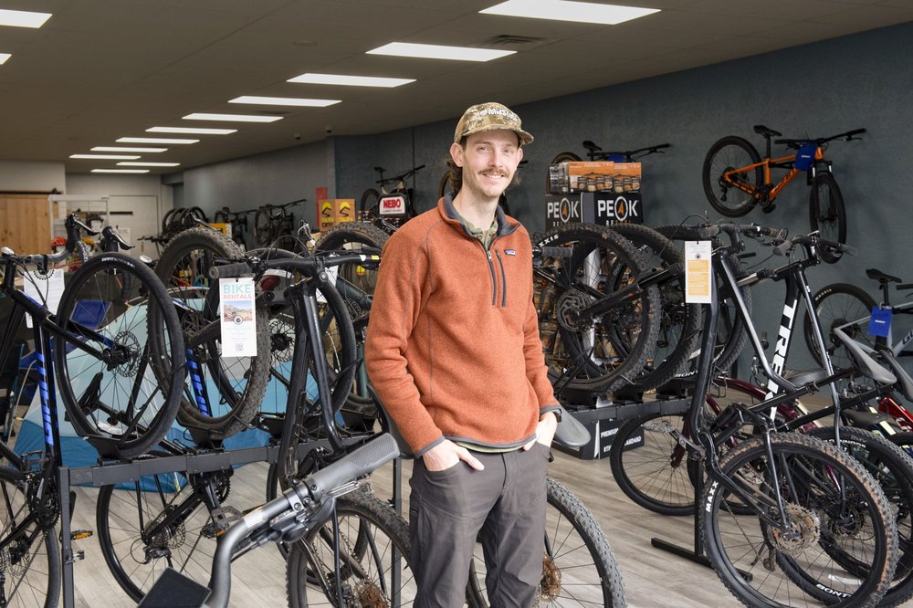A man standing in front of bikes for sale.
