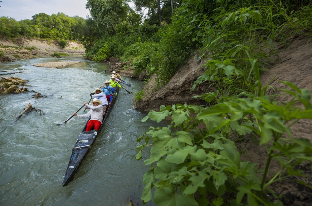 Team of 5 paddling racing canoe down the San Marcos River during Texas Water Safari