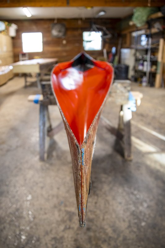 Front view of racing canoe with red epoxy drying in workshop