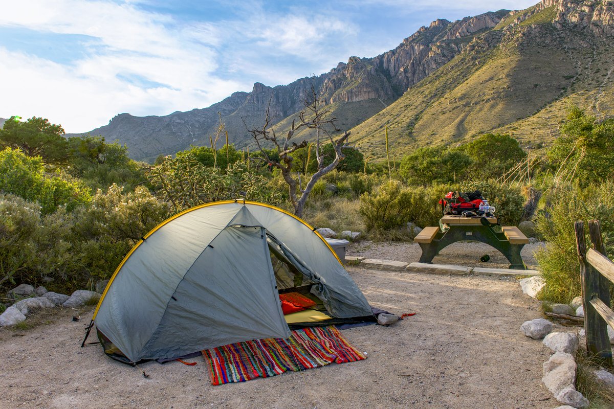 Tent with blanket and sleeping mattress erected at campsite with Guadalupe Mountains in the background