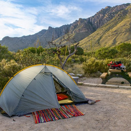 Tent with blanket and sleeping mattress erected at campsite with Guadalupe Mountains in the background