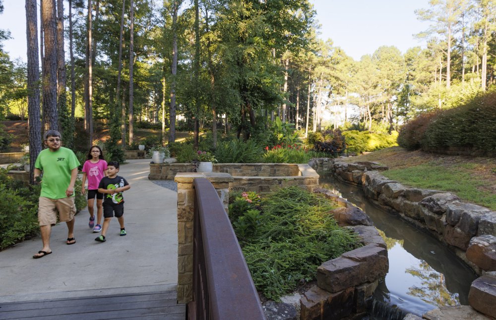 Family walk along the paved trails and canals of water at Longview Arboretum Nature Center in Longview