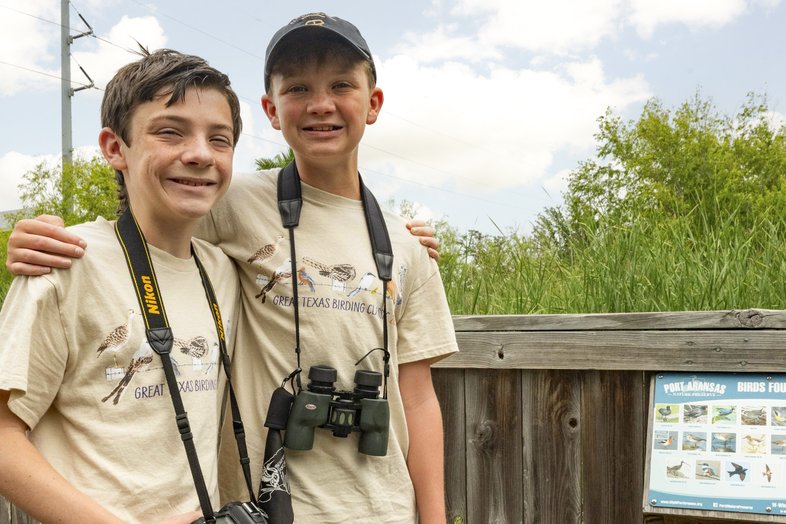 Two children with arms around each other wearing binoculars.