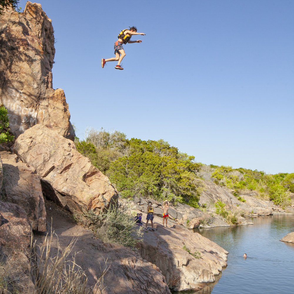 Person jumping of a cliff into the water.