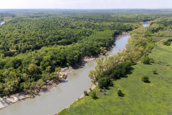 A river surrounded by trees and a field.