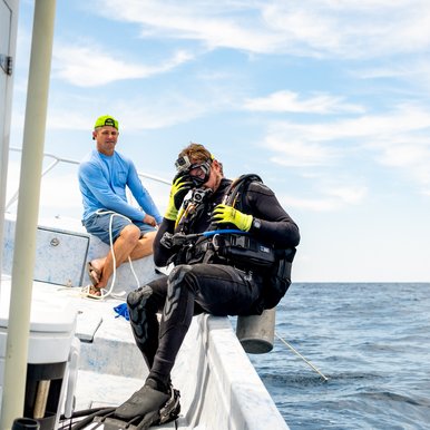 Scuba diver entering choppy water from side of boat.