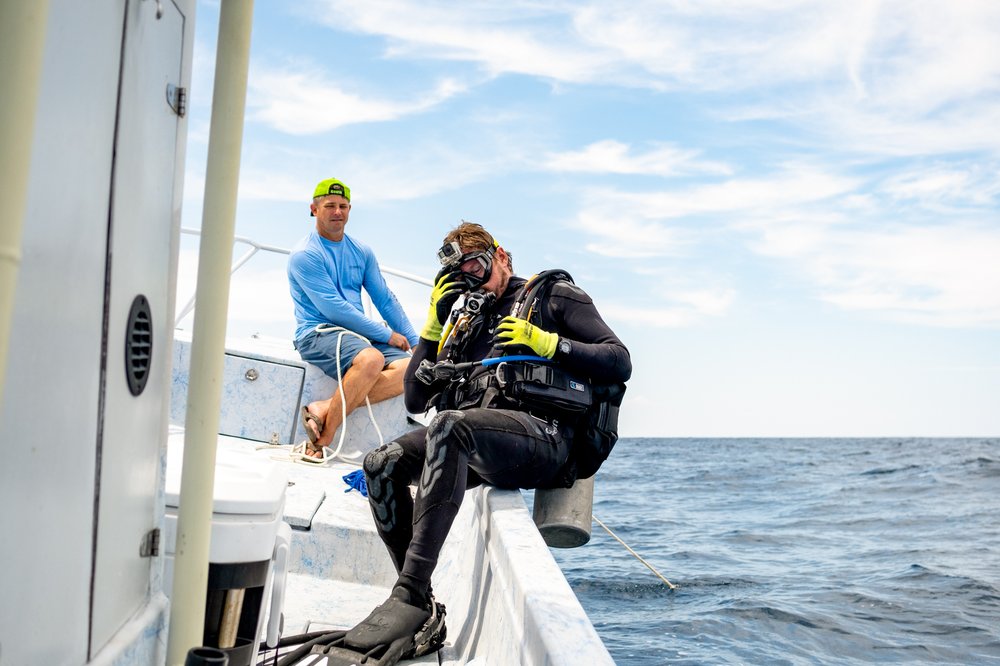 Scuba diver entering choppy water from side of boat.
