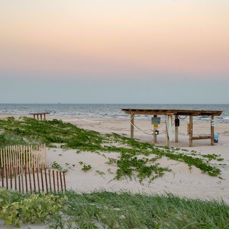 Beach shelter with view of ocean and sunrise.
