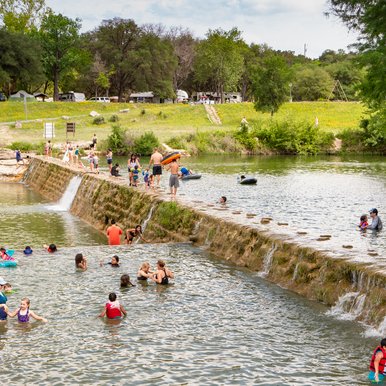 People swimming in the pool built into the Blanco river.