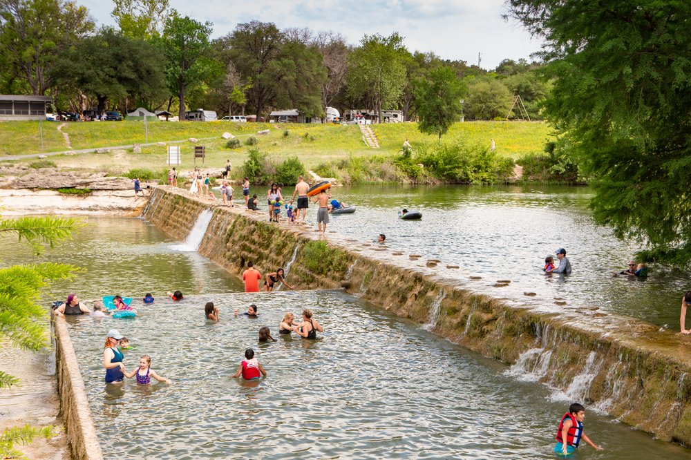 People swimming in the pool built into the Blanco river.