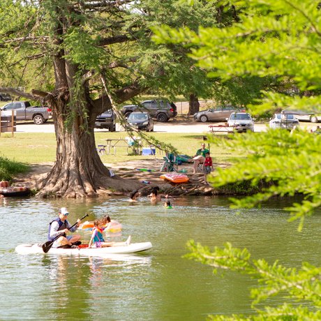 People swimming and paddling on the river.