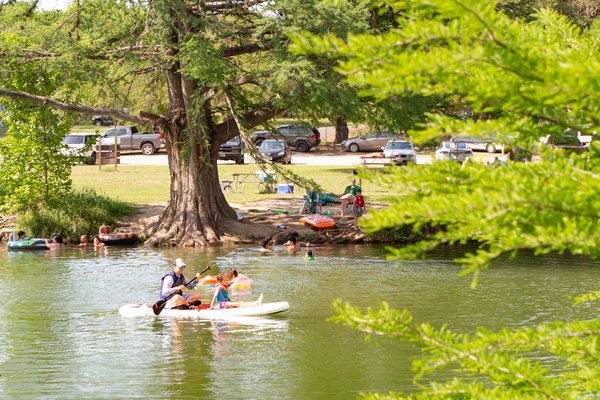 People swimming and paddling on the river.