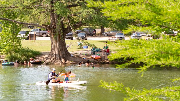 People swimming and paddling on the river.