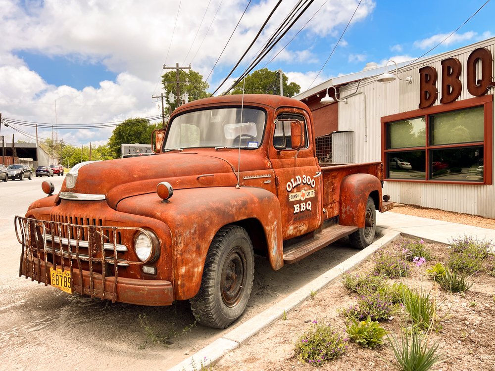 Rusted red vintage truck sitting outside BBQ joint.