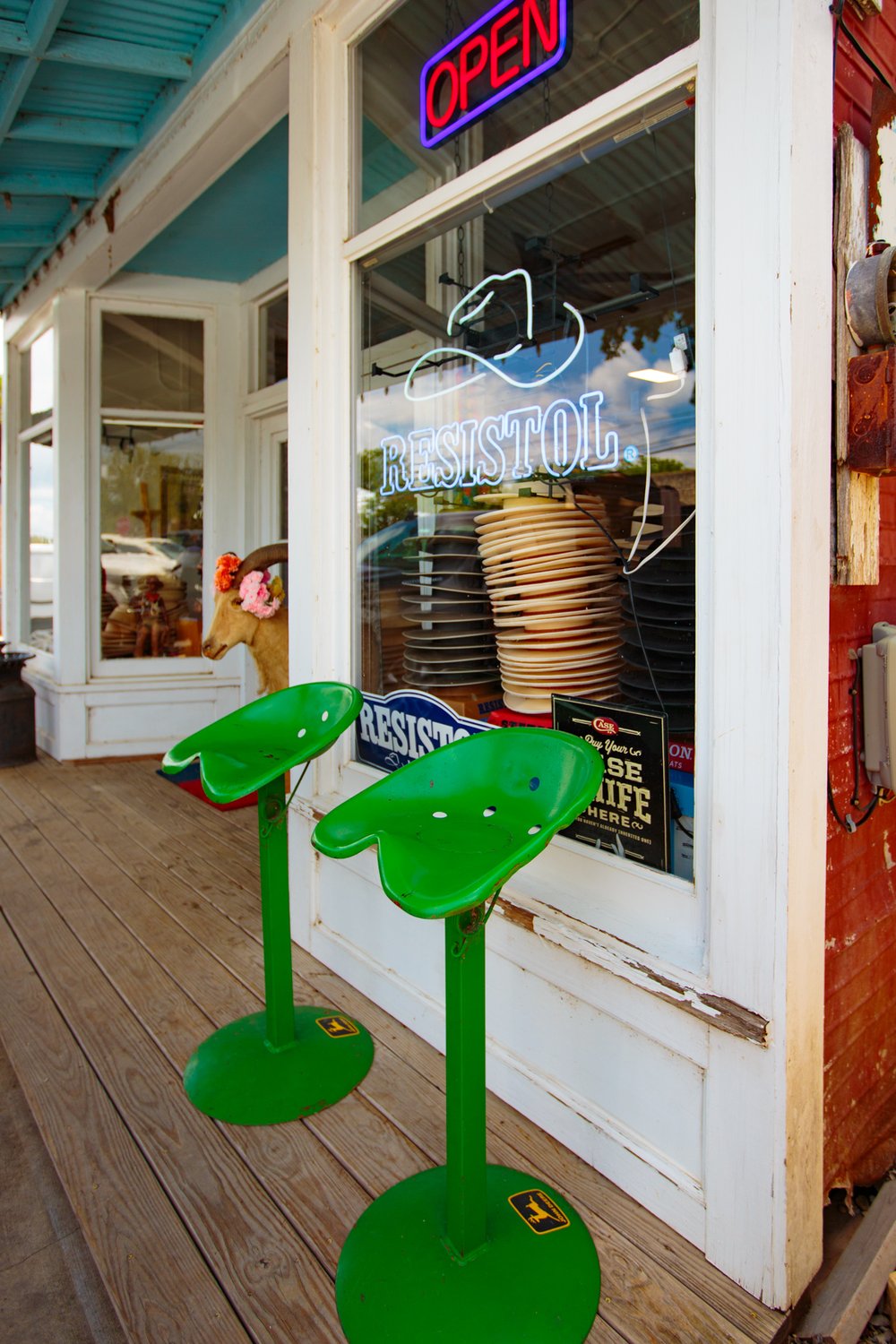 Green tractor style chairs outside a hat shop.