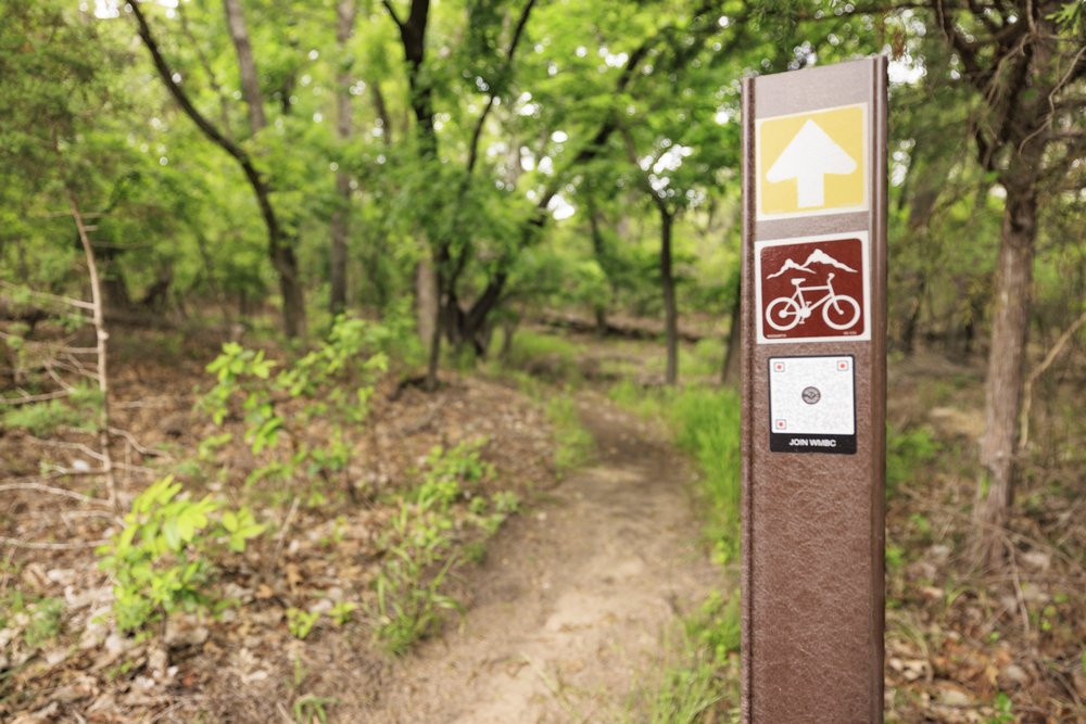 A bike trail sign stands next to the trail at Quanah Hill park in Weatherford
