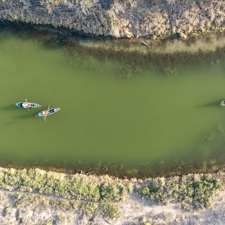 A bird's eye view of two kayakers paddling the green Pecos River