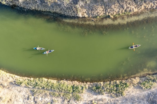 A bird's eye view of two kayakers paddling the green Pecos River