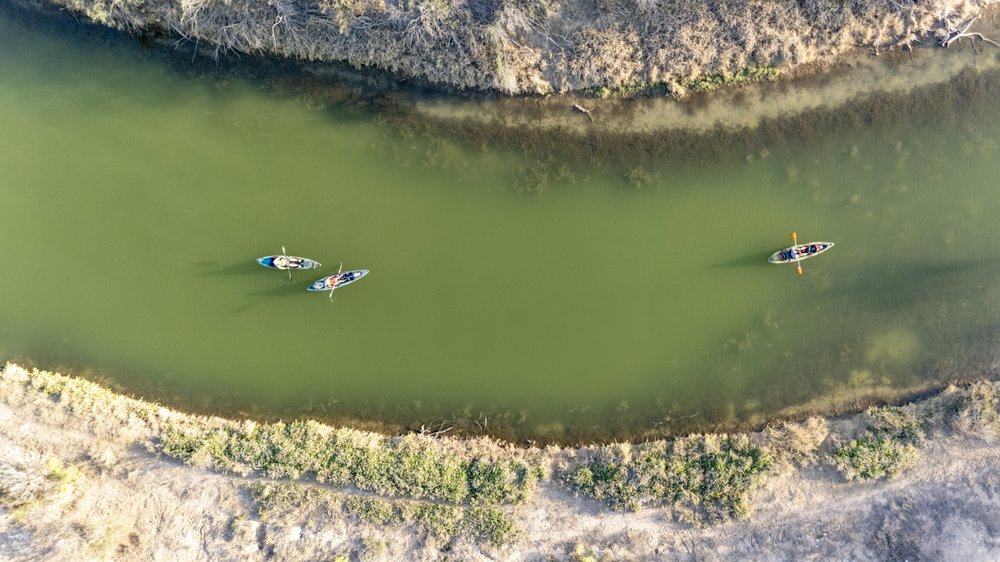 A bird's eye view of two kayakers paddling the green Pecos River