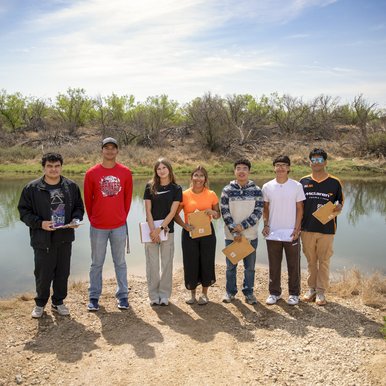 Group shot of volunteers on the banks of Pecos River