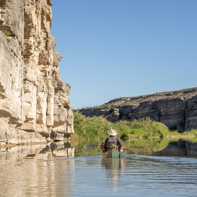 Kayaker paddles along the cliffs of the lower canyon on the Rio Grande River