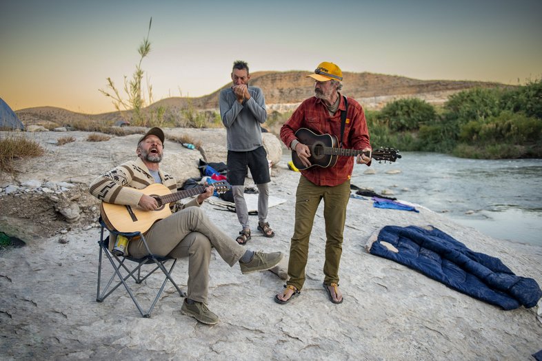 Paddling guides providing musical entertainment at sunset on the banks of the Rio Grande River