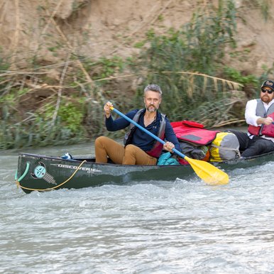 Two paddlers on a canoe navigating the swift waters of the lower canyons on the Rio Grande River