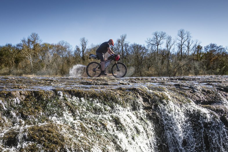 A person riding a bike along a rocky ledge.