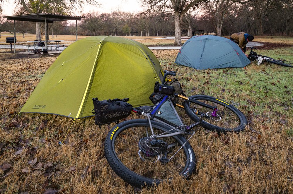 A bike leaning against a tent at a compsite