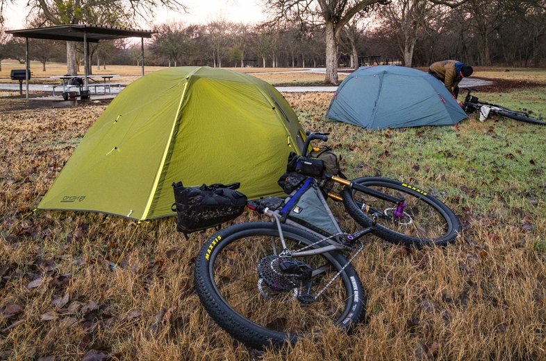 A bike leaning against a tent at a compsite