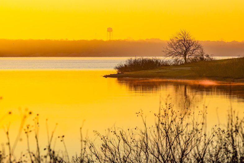 A lake at sunrise with fog on the water.