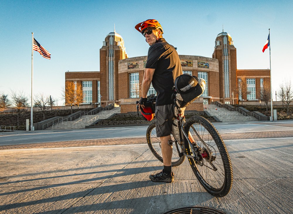 A person on a bike in front of an events center.