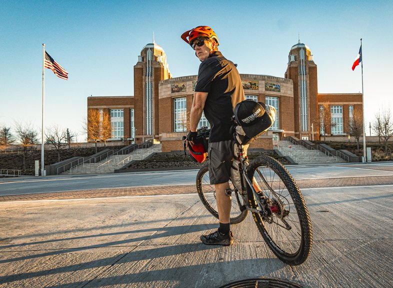 A person on a bike in front of an events center.