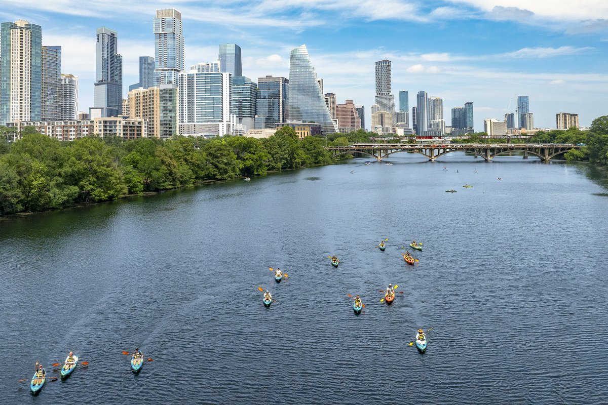 Multiple kayakers on a lake in the city.